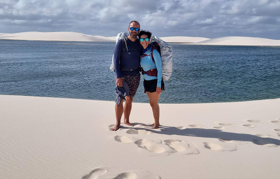 Leticia-e-Dennis-em-um-campo-de-areia-com-agua-ao-fundo.jpg Beach